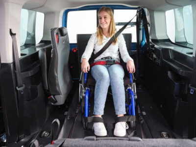 Junge Frau im Rollstuhl im neuen VW Caddy