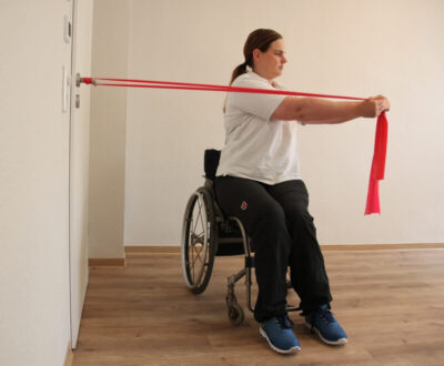 Rollstuhlfahrerin mit Fitnessband bei einer Übung an einer Tür