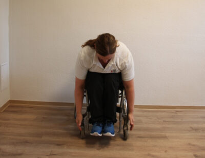 Rollstuhlfahrer bei einer Fitnessübung nach vorne gebeugt