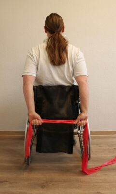 Rollstuhlfahrerin mit Fitnessband bei einer Übung