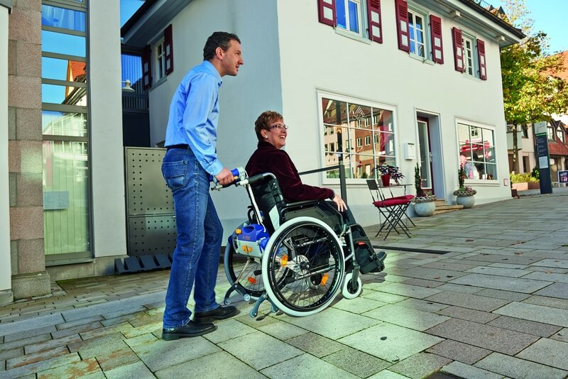Mann der in der Stadt einen Rollstuhlfahrer schiebt