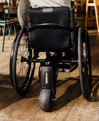 Rollstuhl von hinten mit einem elektrischen Zusatzantrieb