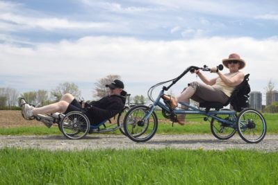 Zwei ältere Menschen seitlich von unten auf Spezailfahrrädern fotografiert