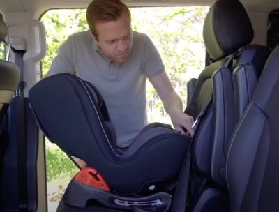 Mann befestigt einen Kindersitz im Auto