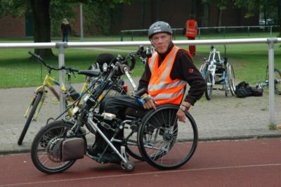 Älterer Mann im Rollstuhl mit Handbike von der Seite