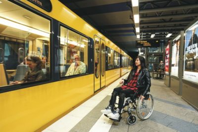 Eine Frau im Rollstuhl steht auf einem U-Bahn-Bahnsteig