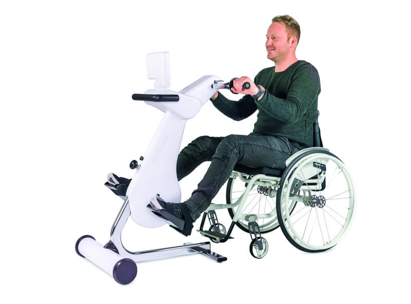 An Mann in einem Rollstuhl sitzend an einem Trainingsgerät für die Arme