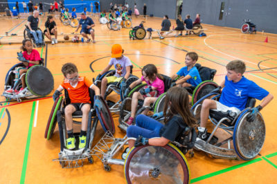 Kinder im Rollstuhl spielen in einer Sporthalle Basketball