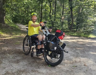 Mann mit Rollstuhl und Handbike im Wald